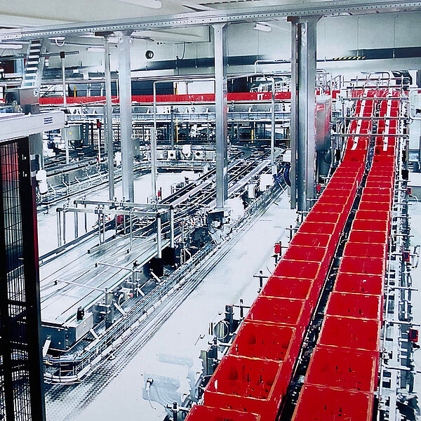 Große automatisierte Verpackungslinie mit roten Transportkisten in einer modernen Industriehalle