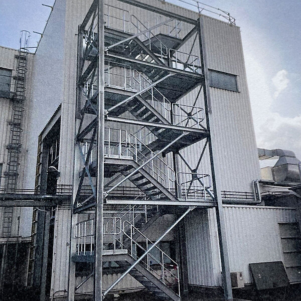 Externe Industriestahltreppe mit mehreren Ebenen an der Fassade eines Chemie- oder Produktionsgebäudes