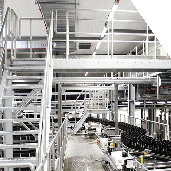 Automatisierte Produktionslinie mit Flaschenförderband und Metallbühnen in einer modernen Industrieanlage.