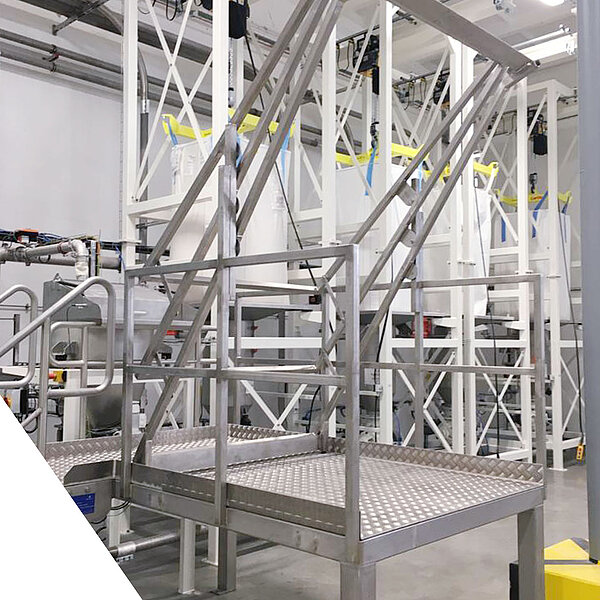 Industrielle Metalltreppe mit Podest in einer automatisierten Produktionsanlage.
