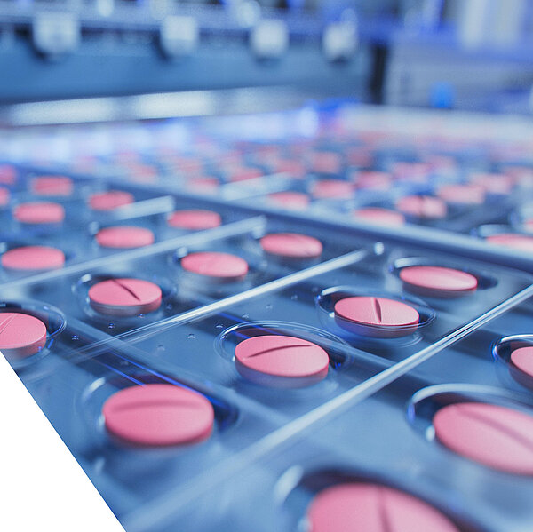 Nahaufnahme einer pharmazeutischen Produktionslinie mit rosafarbenen Tabletten in Blisterverpackungen